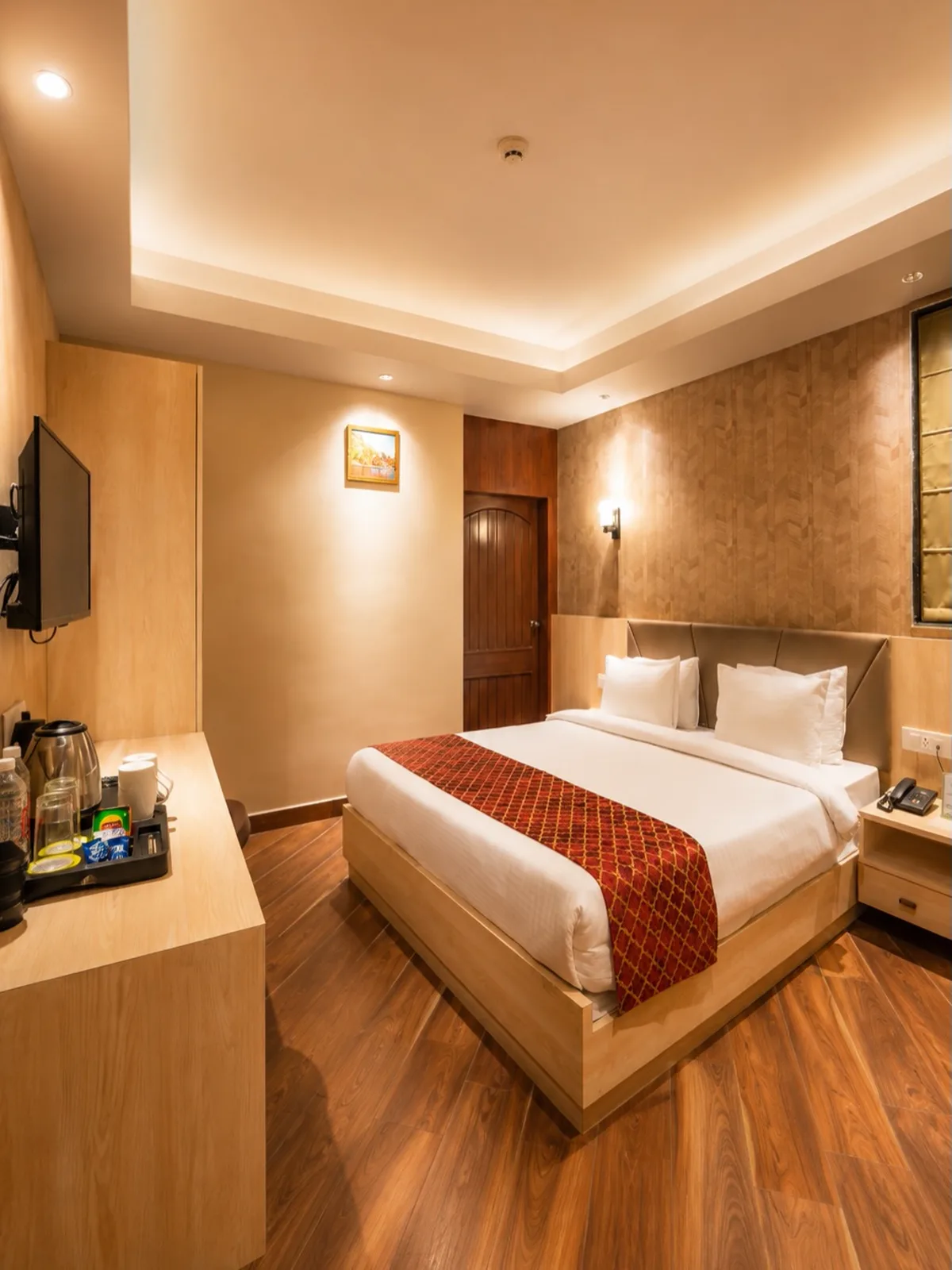Elegant guest bedroom with warm wood tones and a red heritage-patterned bed runner